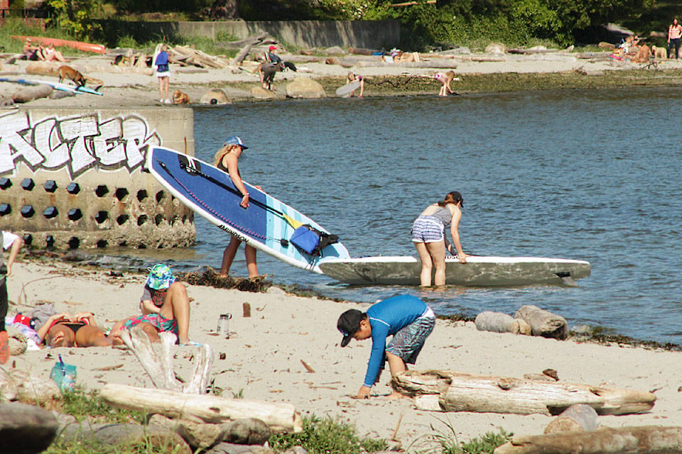 Beach-goers lounge in the sand, hop on paddleboards and explore the surf at Cadboro Bay beach on June 18. (Devon Bidal/News Staff)