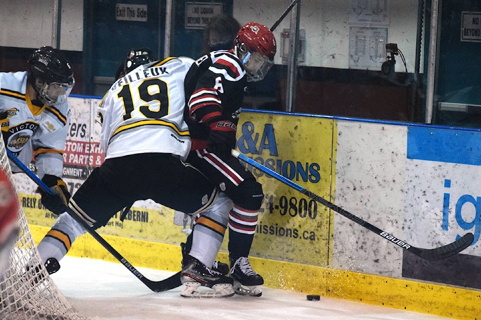 Alberni Valley Bulldogs forward comes away with the puck after a battle along the boards with Grizzlies defenceman Jake Veilleux. (ELENA RARDON / ALBERNI VALLEY NEWS)