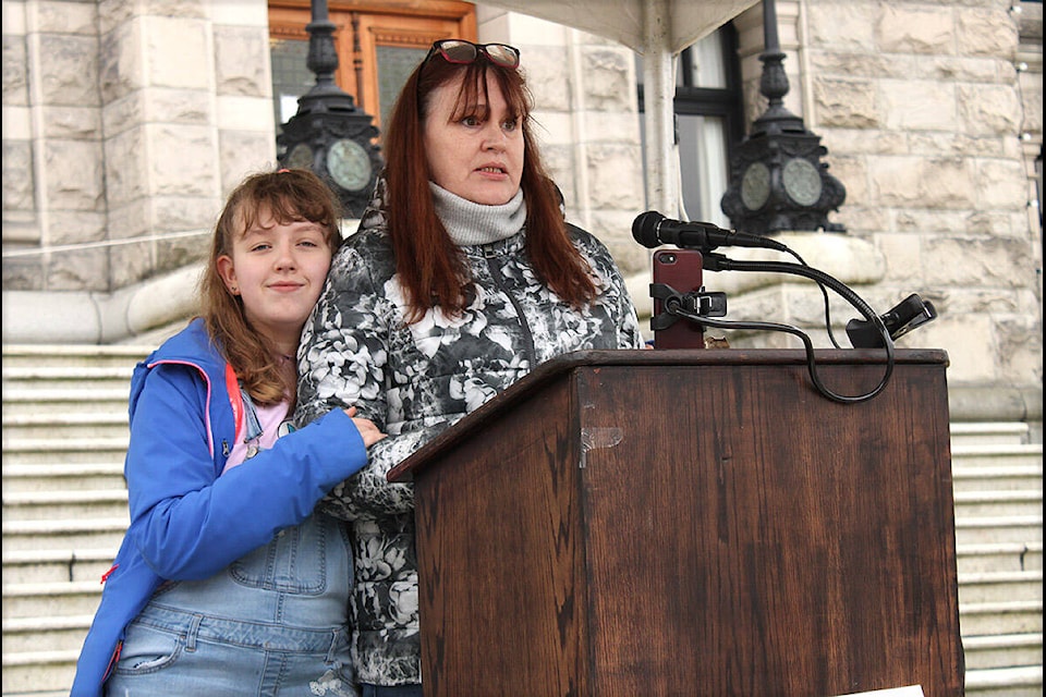 Diane Pearce, right, with her daughter Madison Ross, speaks at a rally Wednesday (Feb. 9) outside the legislature that called on the province to end its planned phase-out of individualized autism funding. (Jake Romphf/News Staff)