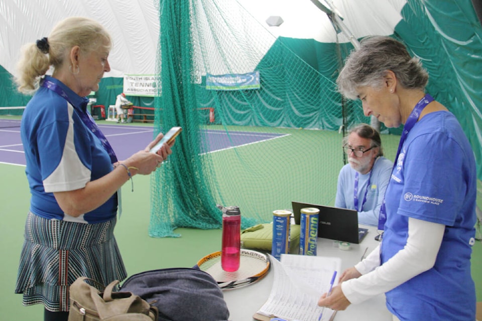 Daphne McFarland (left) learns when her consolation game is after a loss at the Oak Bay tennis bubbles while Greater Victoria 2022 55+ BC Games volunteers Art Hobbs (centre), sport chair for tennis, and Sophia Sperdakos collect information. (Christine van Reeuwyk/News Staff)