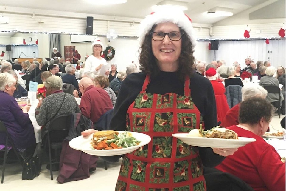 Merilyn Lentz serves up dinner during the annual Monterey centre Christmas dinner on Dec. 15 in Oak Bay. (Christine van Reeuwyk/News Staff)