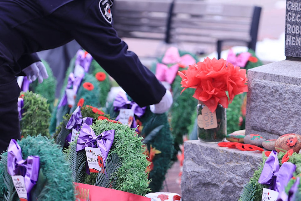 A Grand Forks first responder lays a poppy next to a “thank you” vase at the foot of the cenotaph outside city hall. Photo: Laurie Tritschler