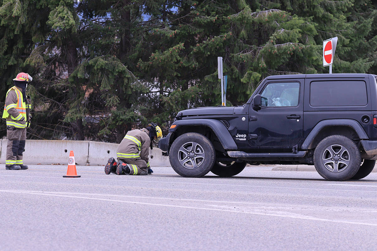Grand Forks Fire/Rescue members clean up an oil spill under a Jeep which came into collision with another car on Highway 3, near Spraggett Road on Friday, April 9. Photo: Laurie Tritschler