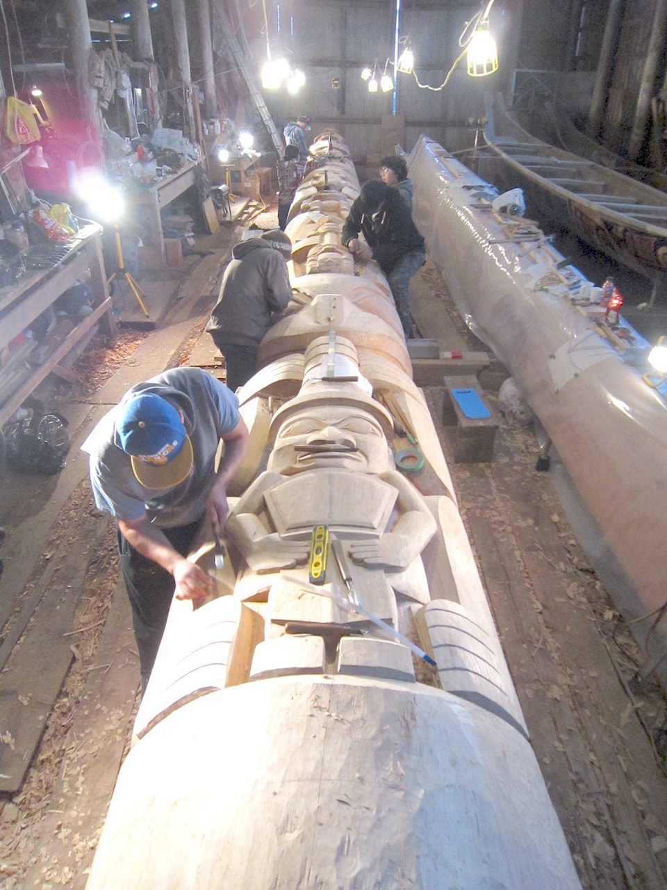 Haida artists carve on a 50-foot totem pole.