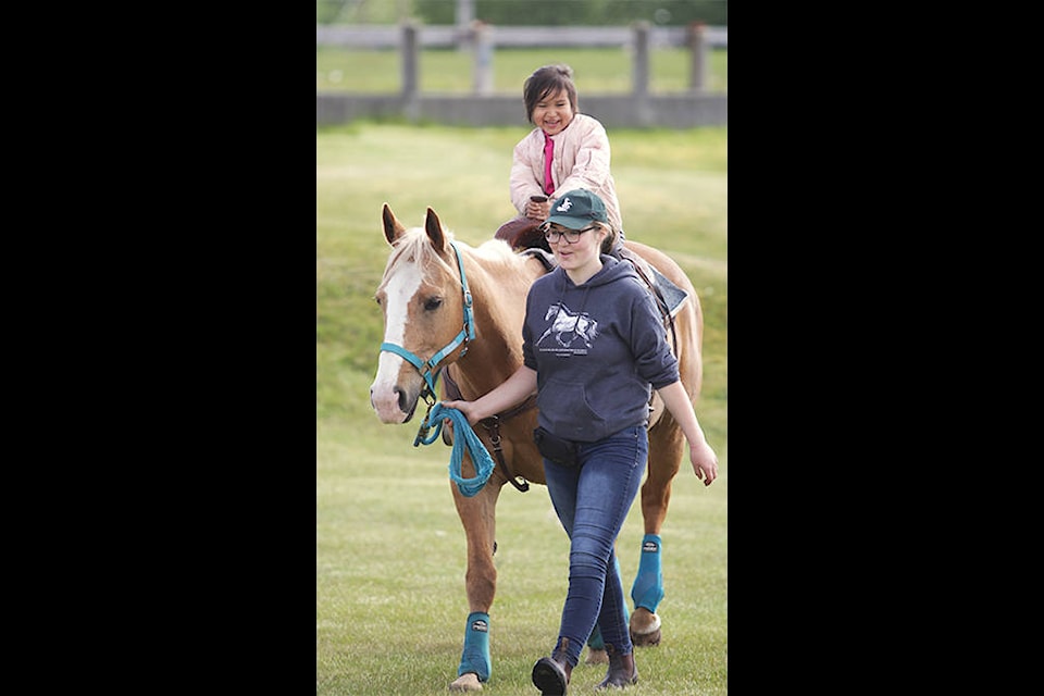 Four-year-old Zona takes a ride with Barbie, led by Jessica Collison. It was Zona’s first time on horseback. (Andrew Hudson/Haida Gwaii Observer)