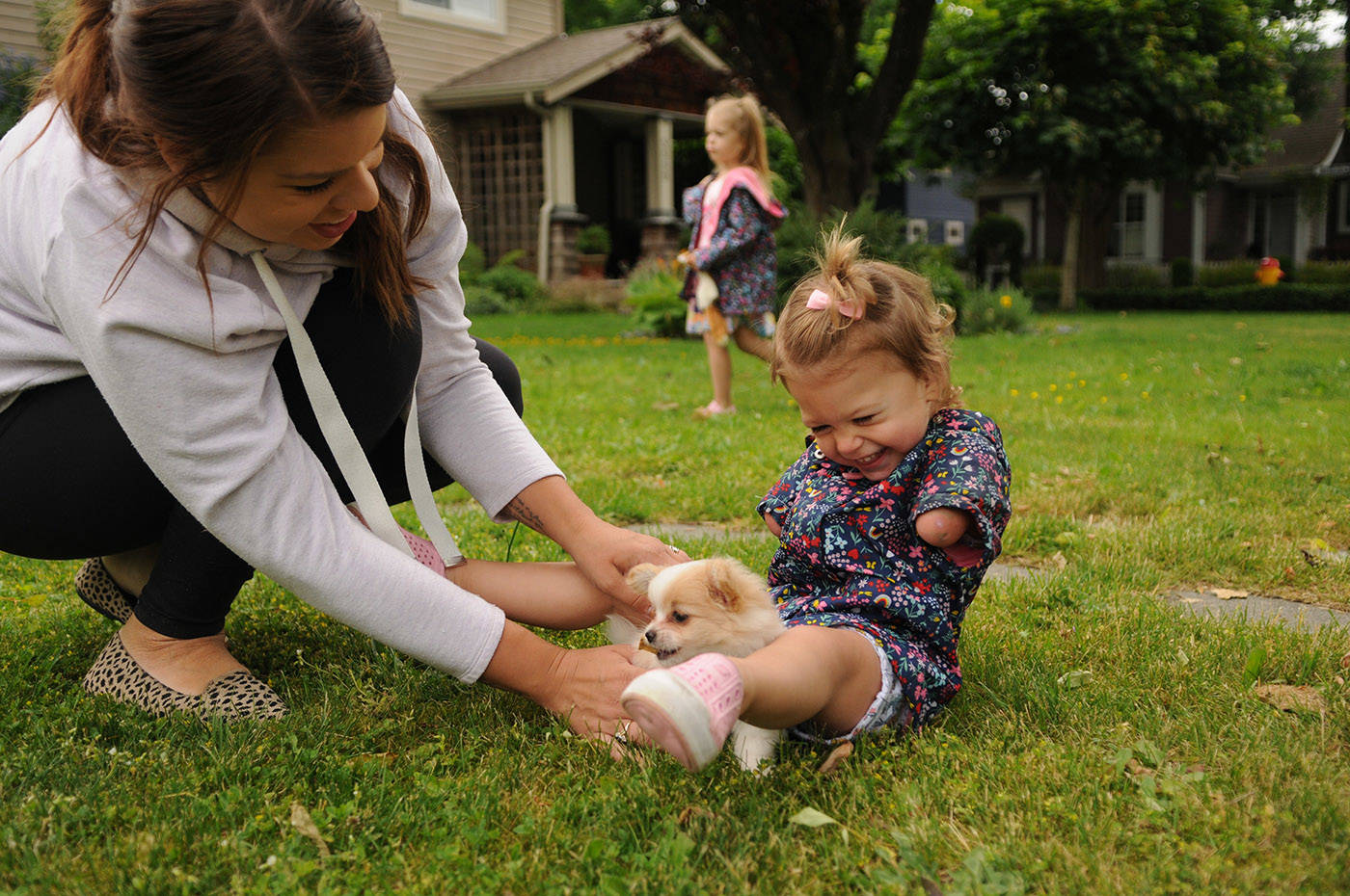 Two-year-old Ivy McLeod laughs while playing with Lucky the puppy outside their Chilliwack home on Thursday, June 10, 2021. (Jenna Hauck/ Chilliwack Progress)