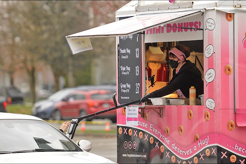 A transaction is made at the Hugs Donuts vendor during the Greater Vancouver Drive-Thru Food Truck Festival at the Chilliwack Coliseum parking lot on Saturday, March 27, 2021. (Jenna Hauck/ Chilliwack Progress)