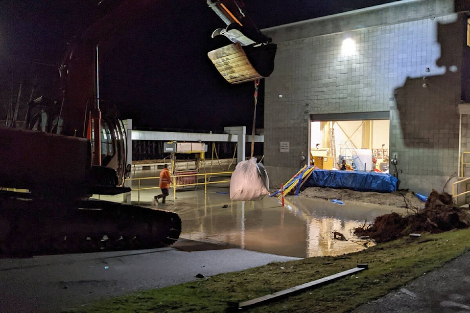 Crews work to protect an Abbotsford pump station from encroaching flood water. (@ErikDV Twitter photo)
