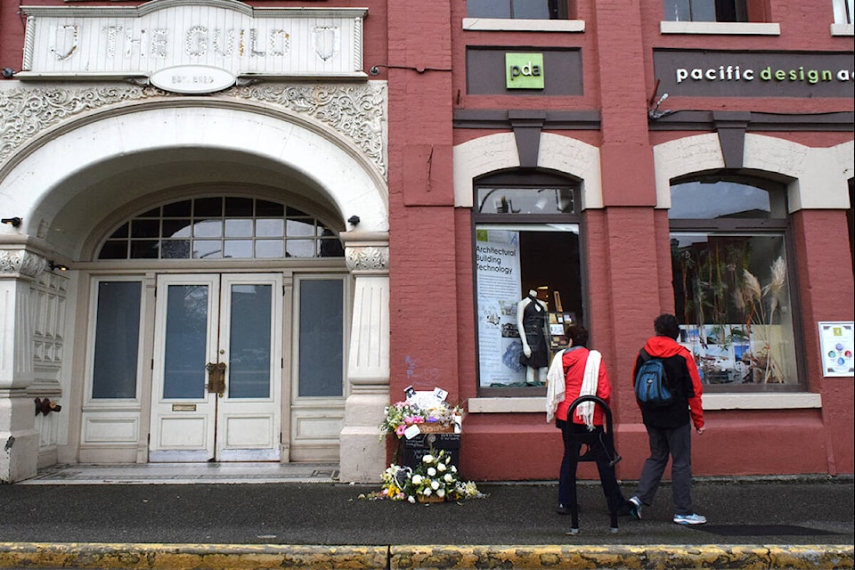 Victoria residents take a brief moment to examine the flowers, stuffed animals and photos left in remembrance of 17-year-old Olivia Mahaney, who died of overdose at the corner of Wharf and Yates streets. (Kiernan Green/News Staff)