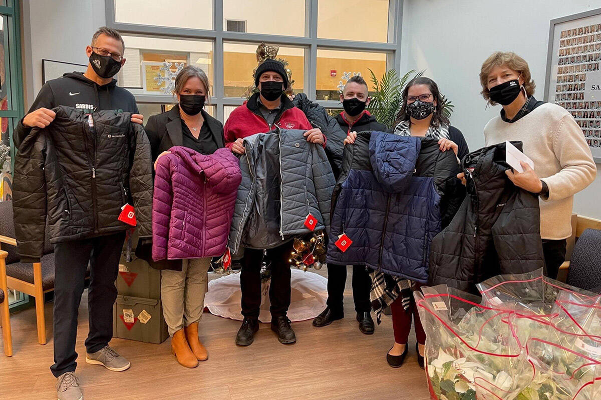 John Boris, general manager of Canadian Tire in Chilliwack (in red), and Justin Mallard with Murray Honda (third from right) show off some of the coats delivered to Sardis secondary school as part of the Coats for Kids program. (Submitted by Justin Mallard)