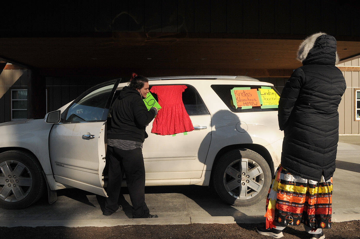 Lindsey Bishop (left) and Krista Fox put signs and a red dress on their vehicle before starting their 17.5-kilometre journey from Squiala First Nation to Cheam First Nation as part of a cross-Canada walk on Friday, Feb. 25, 2022. The two are from Saskatchewan and are doing the 7,426-kilometre walk to raise awareness for missing and murdered Indigenous women. (Jenna Hauck/ Chilliwack Progress)