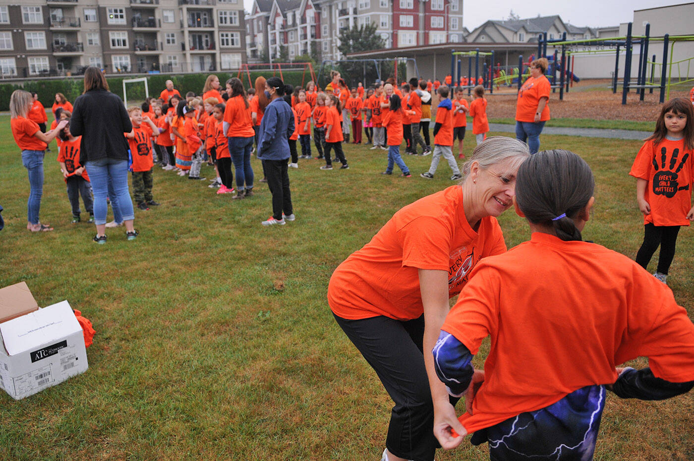 A child gets help putting on an orange T-shirt before a group photo at Bernard Elementary on Thursday, Sept. 29, 2022. The schools parent advisory council bought an orange T-shirt for every single student at Bernard. (Jenna Hauck/ Chilliwack Progress)