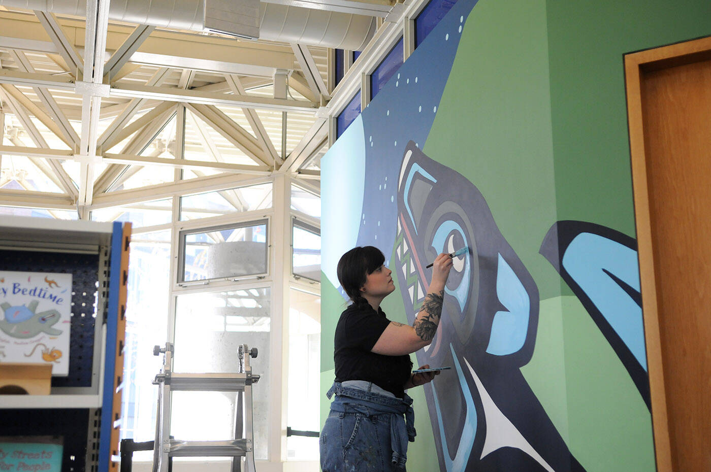 Artist Chantelle Trainor-Matties works on her mural at the Chilliwack Library on Nov. 8, 2022. (Jenna Hauck/ Chilliwack Progress)