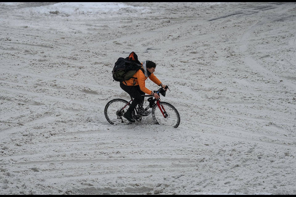 A cyclist navigates through the snow on an unplowed Robson Street as freezing rain falls in downtown Vancouver, on Friday, December 23, 2022. THE CANADIAN PRESS/Darryl Dyck