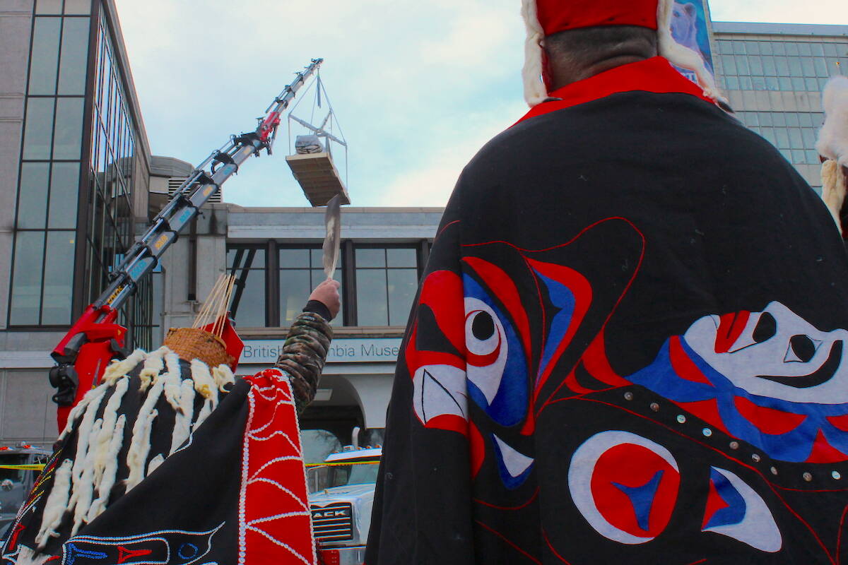 A totem pole is removed and lowered from the Royal B.C. Museum on Feb. 13 as Nuxalk Nation members and others watch on. The totem pole is being repatriated to the Bella Coola territory, its original home before it was taken. (Jake Romphf/News Staff)
