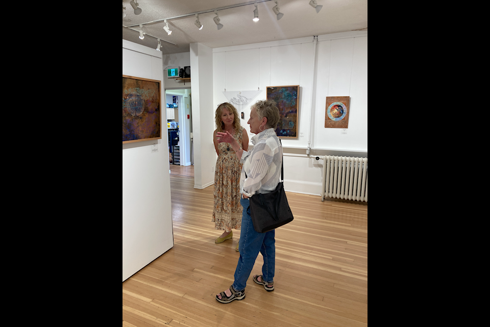 Betty Kovacic and a visitor at the opening night of her art exhibit, We Are One, at the Smithers Art Gallery. 