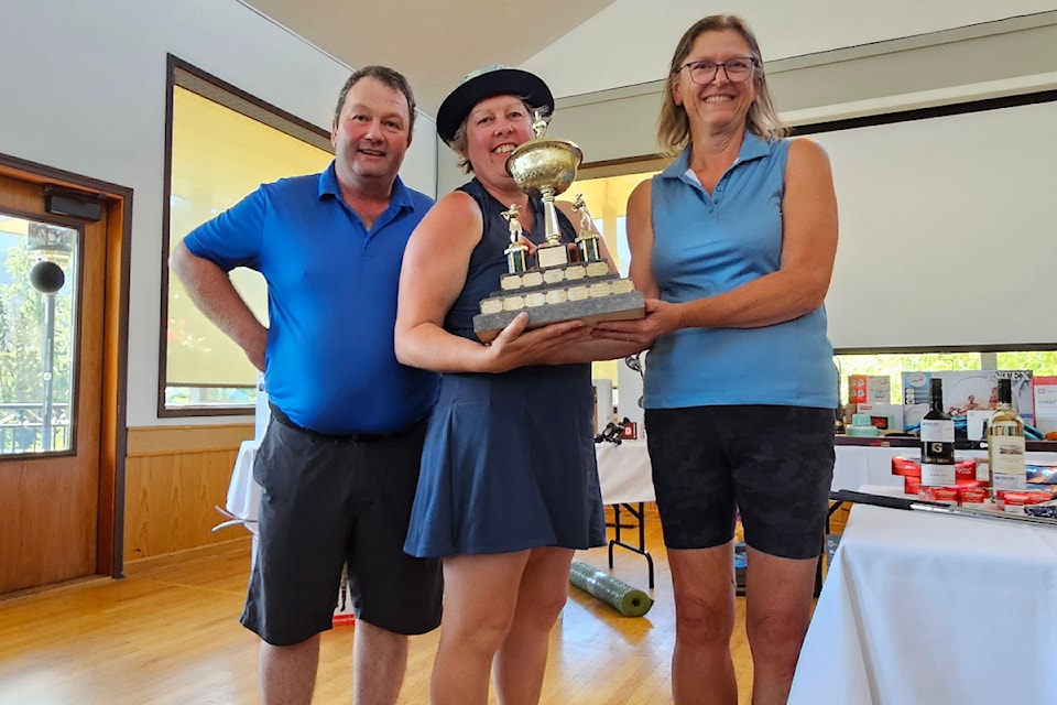 Mr. and Mrs. Golf Tournament committee member Janice Malkow (right) presents the championship trophy to Ann and Philip Maher. 