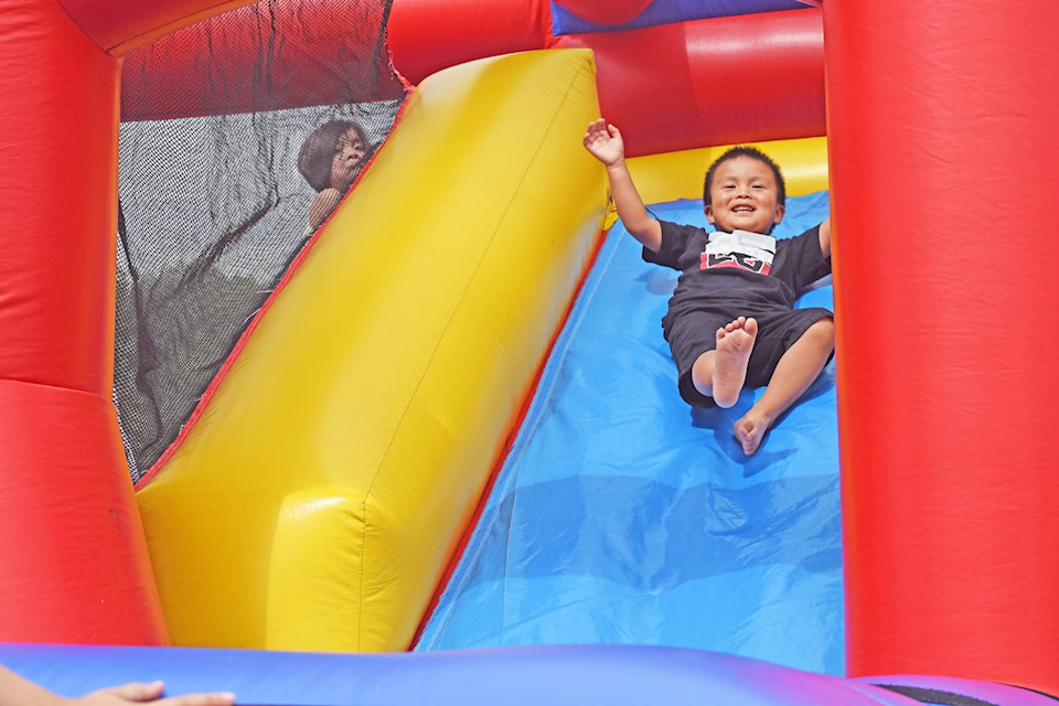 Kids play on a bouncy castle; A child holds onto a balloon; The day also offered activities like a mock firefighter course for children; A volleyball pitch was also available. (Trevor Hewitt photos)