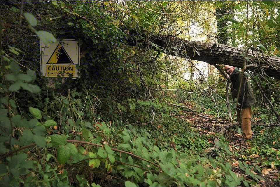 Homeowner Richard Holmes stands in his driveway near a sign that notes ‘Risk of slope failure’ on Oct. 17, 2023. (Jenna Hauck/ Chilliwack Progress file)