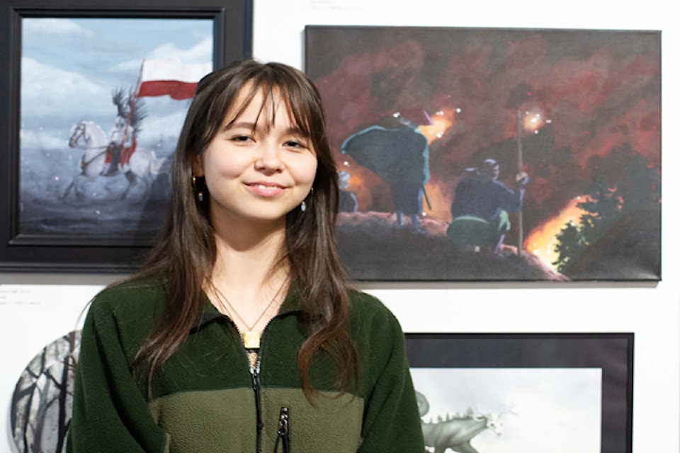 A student artist stands next to their work in Art in Action: Inspiring Awe (April 2024).