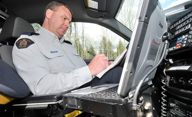RCMP Cpl. Drew Grainger in his car working on his computer