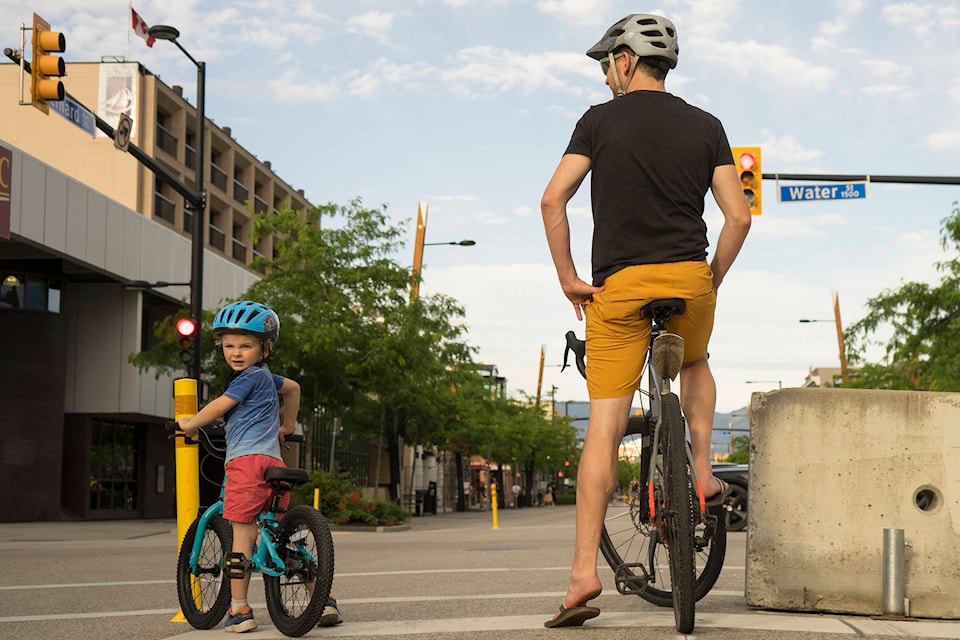 A man and a young boy stopped on their bikes at the intersection of Bernard Avenue and Water Street on Monday, June 29. (Michael Rodriguez - Capital News)