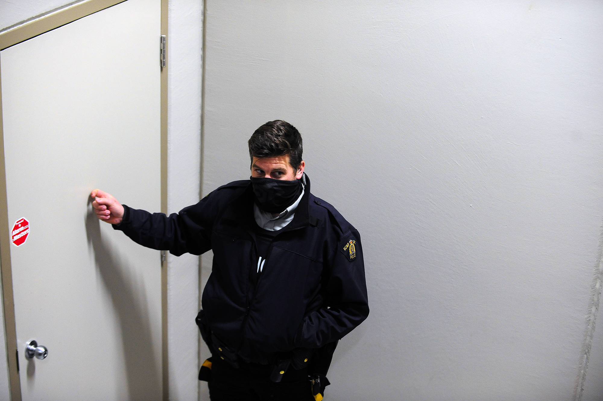 An RCMP officer knocks on the door where parishioners of Kelowna Harvest Fellowship are gathering on Sunday, Jan. 10. (Michael Rodriguez - Capital News)