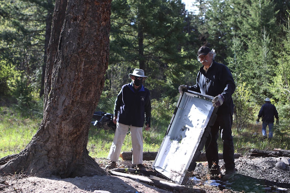 Peachland resident and cleanup volunteer Lloyd Stinson Sotas holds up a discarded TV riddled with bullet holes. (Aaron Hemens/Capital News)