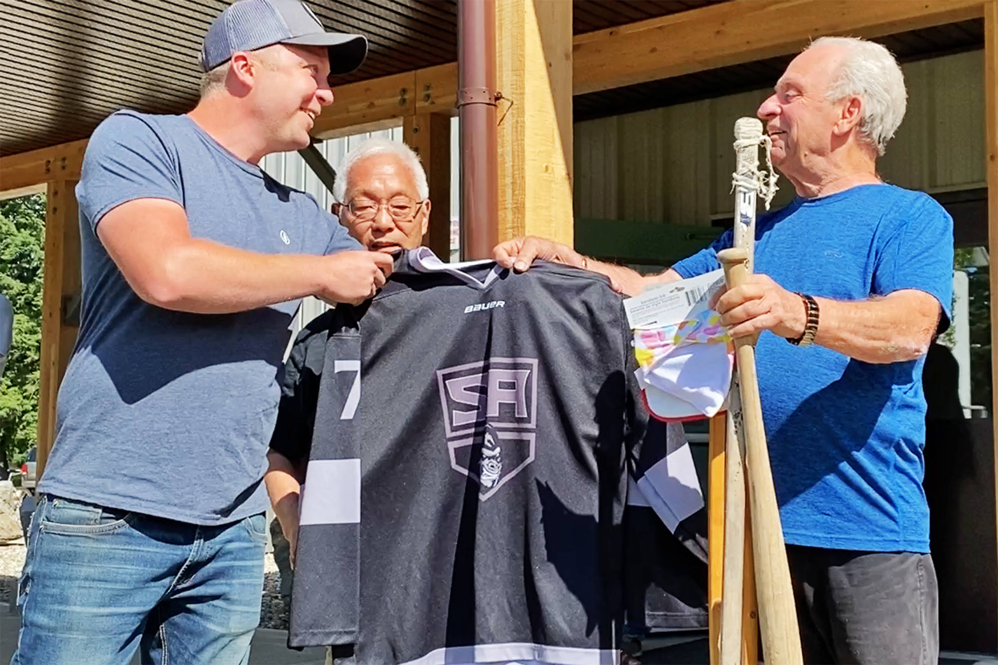 Salmon Arm Minor Hockey聮s Mark Delleman and Roy Sakaki present Wayne March with a Salmon Arm Silverbacks jersey during a surprise gathering for March on Thursday, June 10, 2021. (Lachlan Labere-Salmon Arm Observer)