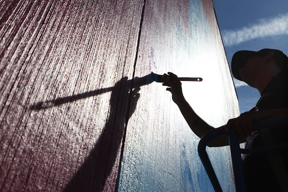 Syilx artist Sheldon Pierre Louis works on his “We Are Medicine” mural on the wall of 鶹ѡ’s Gospel Misson on Sept. 7. (Aaron Hemens/Capital News)
