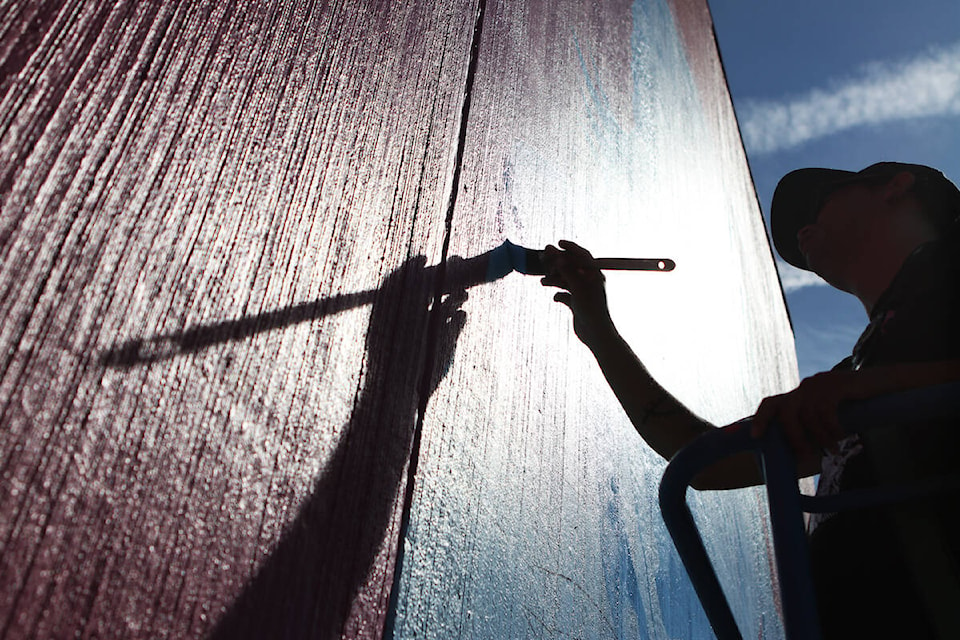 Syilx artist Sheldon Pierre Louis works on his “We Are Medicine” mural on the wall of Kelowna’s Gospel Misson on Sept. 7. (Aaron Hemens/Capital News)