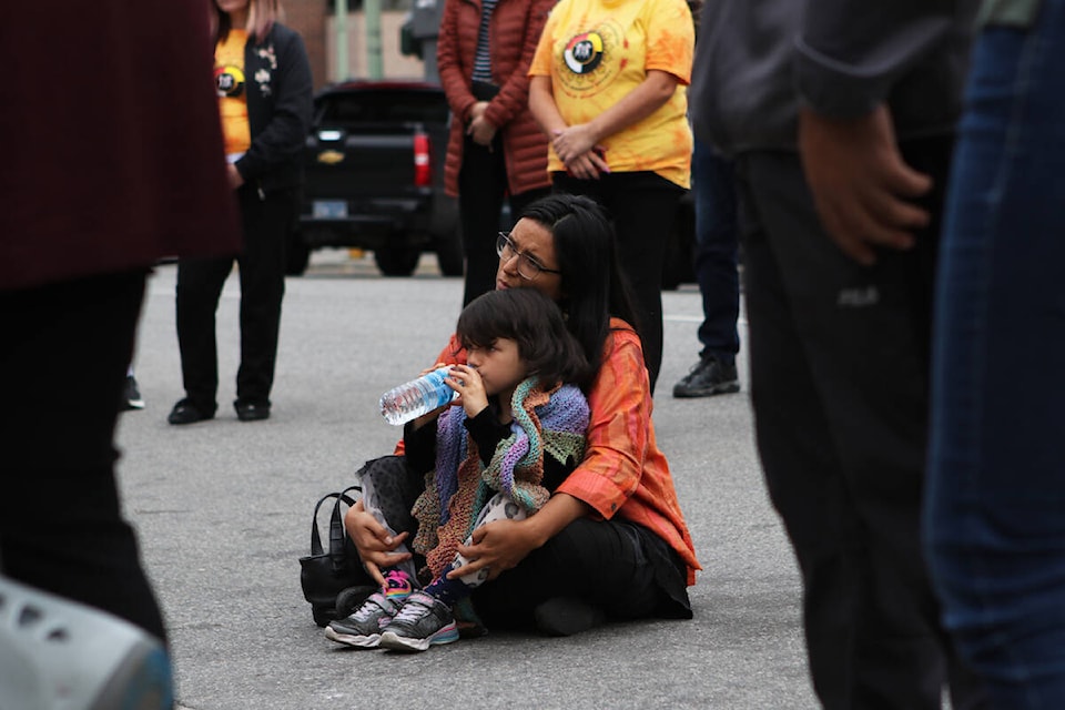 A child sits on a woman’s lap outside of the entrance of the Ki-Low-Na Friendship Society on Sept. 29 during the group’s ceremony that honoured the inaugural National Day for Truth and Reconciliation on Sept. 30. (Aaron Hemens/Capital News)