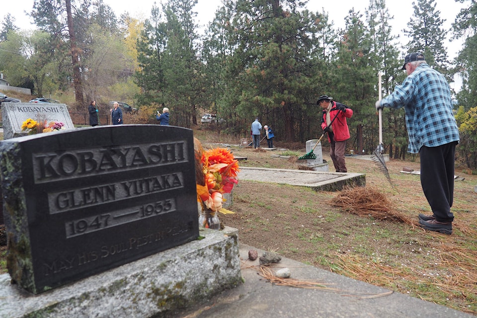 Beyond a gravestone, Tom Watson (Lion, front) and Gary Baird (Rotary) rake up six months worth of pine needles. (Jim Taylor - Contributed)