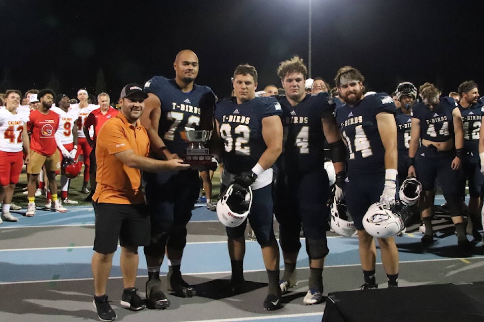 Kal Tire’s Ryan Paulson (left) presents the first Kal Tire Kalamalka Bowl to UBC Thunderbirds captains Manu Giovanni (from left), Kyle Samson, Gavin Coakes and Ryan Baker after the T-Birds defeated the Calgary Dinos 28-10 in the first Canadian U-Sports exhibition football game played in the North Okanagan at Greater Vernon Athletic Park Wednesday, Aug. 24. (Darren Hove photo)