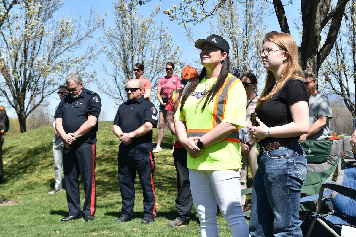 Members of the Kelowna Fire Department (left) and Danielle Pritchett hold their heads down during a moment of silent at the 2023 Day of Mourning. (Jordy Cunningham/Capital News)