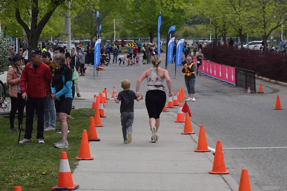 Kimberly Brunet running to the finish line with her son at the 2023 Cherry Blossom Triathlon in Kelowna. (Brittany Webster/Capital News)