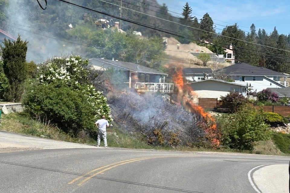 A local resident watches a brush fire burning along Princeton Avenue in Peachland on May 6, 2025.
