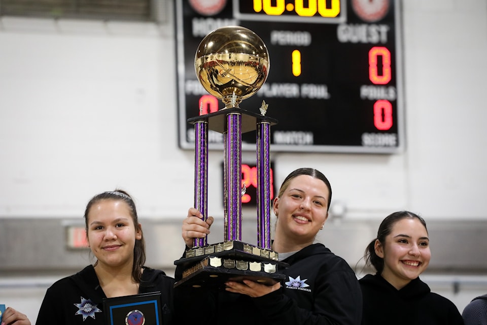 Madison Terbasket of the Similkameen Starbirds, centre, with Waverly Butler and Mikkeila Ridsdale, hoists the women’s division championship trophy following the team’s victory against “Vancouver’s” All My Relations team at the 2025 All Native Basketball Tournament on Feb. 15. Photo by Aaron Hemens