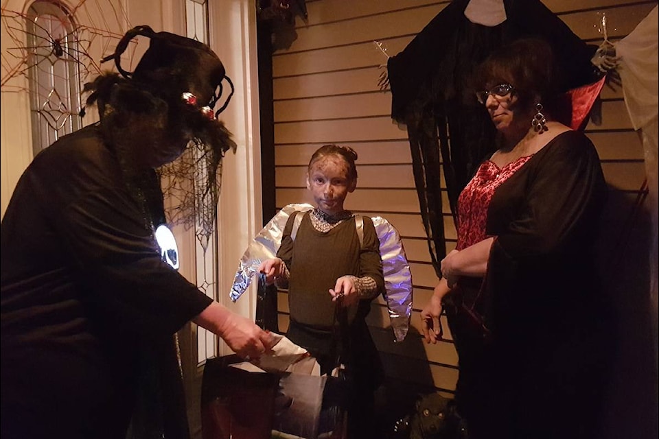 Cathie Wells gives treats to trick or treaters Trinity Russell and Traci Russell. (Stef Laramie photo)