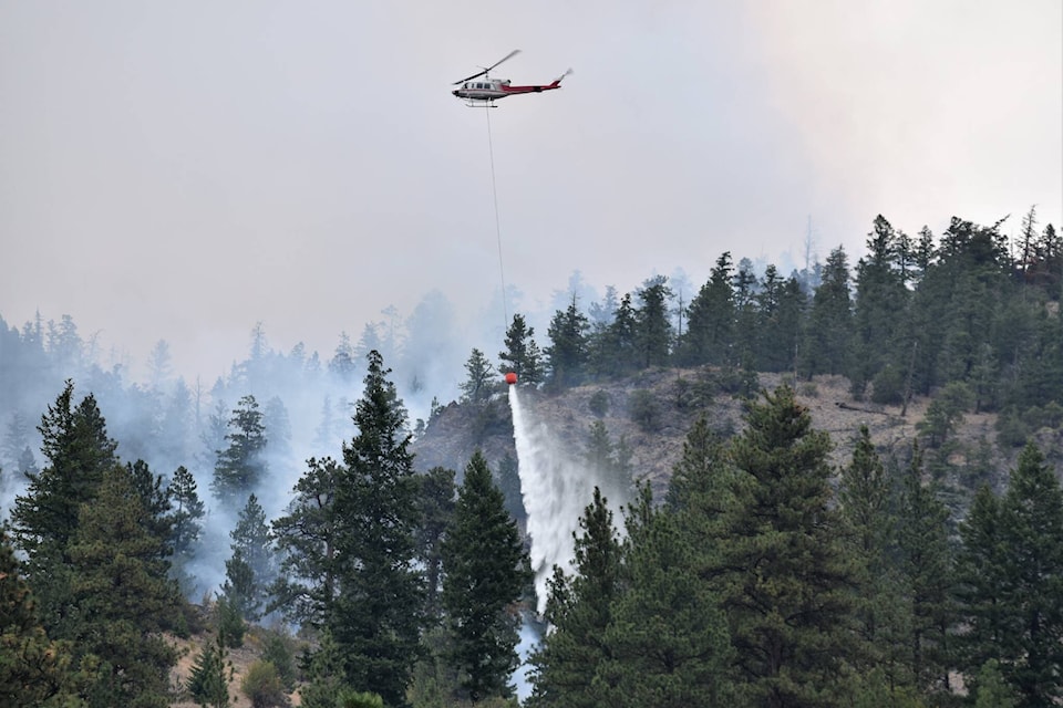 A helicopter bucketing water onto the Hedges Butte wildfire between Penticton and Apex. (Brennan Phillips - Western News)