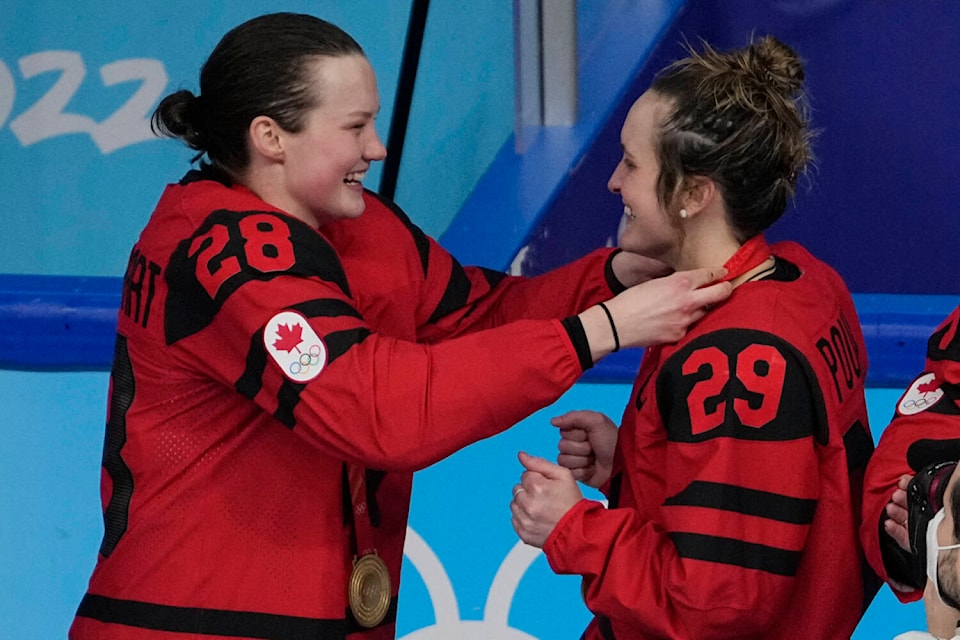 Canada’s Micah Zandee-Hart (28) puts a gold medal on teammate Marie-Philip Poulin (29) after defeating the United States in the women’s gold medal hockey game at the 2022 Winter Olympics, Thursday, Feb. 17, 2022, in Beijing. (AP Photo/Jae C. Hong)
