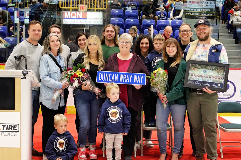 Later former Vernon Vipers team owner Duncan Wray’s family gathers for a photo at centre ice prior to the Snakes’ BCHL home opener Saturday, Sept. 23. The roadway into Kal Tire Place off 43rd Avenue has been named Duncan Wray Way, and his widow, Libby, holds the sign. A banner remembering Wray was raised to the rafters inside Kal Tire Place. (Lisa Mazurek - Vernon Vipers Photography)