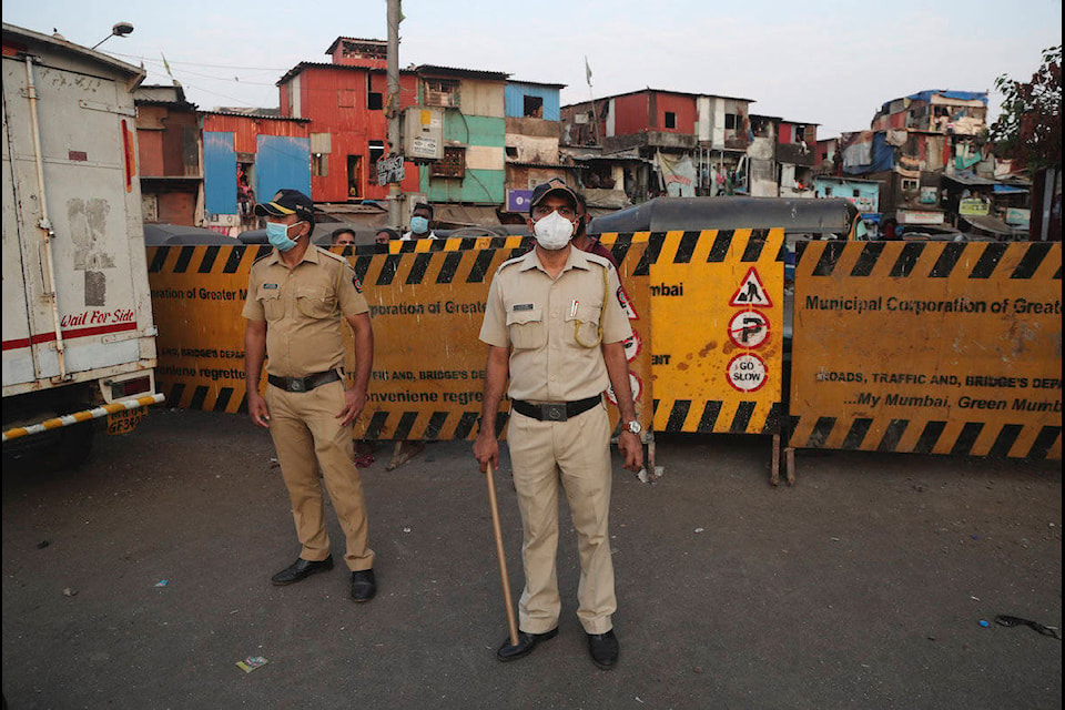 Indian policemen stand guard after a protest against the extension of the lockdown, at a slum in Mumbai, India, Tuesday, April 14, 2020. (AP Photo/Rafiq Maqbool)