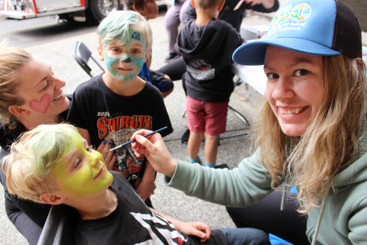 Face-painted twins Waylon and Wilde Van Seters, coming up to 5 in July, become colourful with Rachel Woodruffs artistry while mom Danielle admires the results. (Photo by Don Bodger)