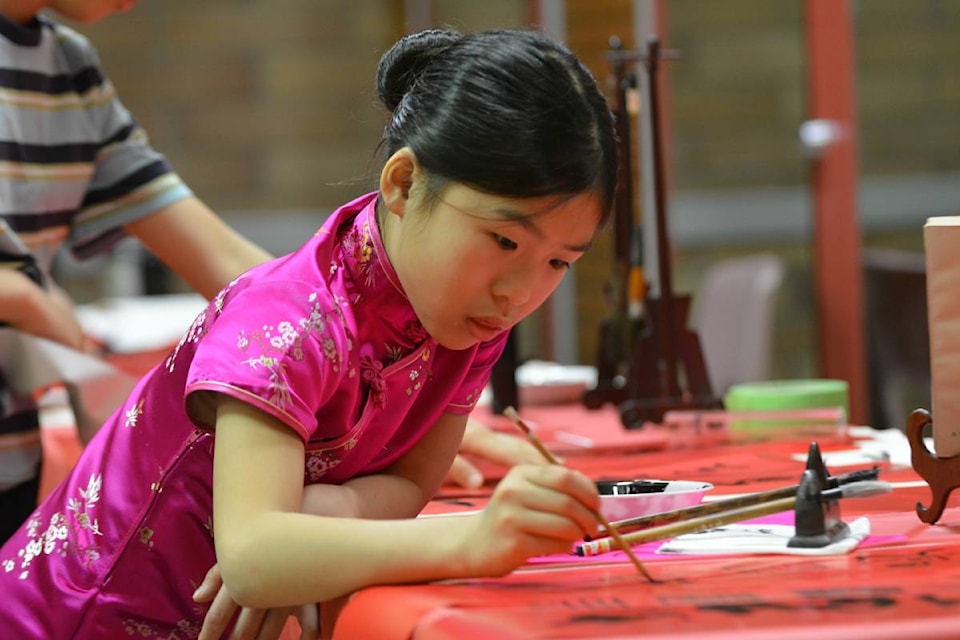 Amelia-Ahn Lou, eight, practices her Chinese calligraphy Saturday night during the eight annual Lantern Festival to celebrate the Chinese New Year. - Credit: Carli Berry/Capital News