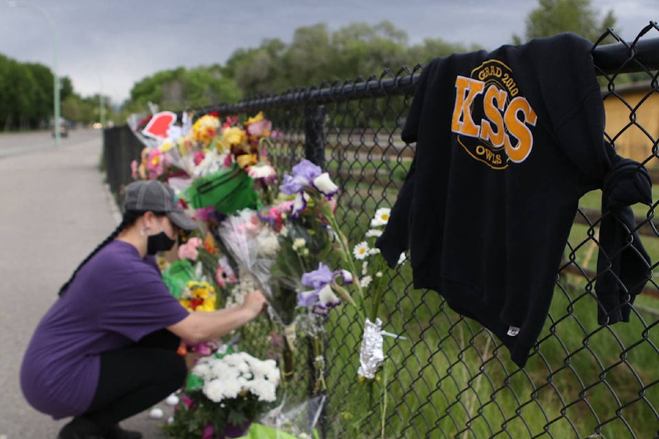 Nicole Spletzer, a Grade 12 student at Kelowna Secondary School (KSS), places a flower bouquet at a makeshift memorial for the three KSS students who were killed in a single-vehicle car accident on Wednesday (May 26). (Aaron Hemens/Capital News)