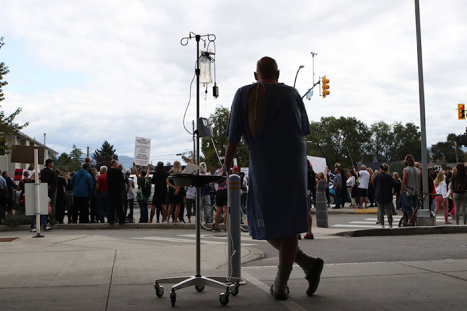 A Kelowna General Hospital patient watches the protest unfold outside, as roughly 1,000 people gathered and protested COVID-19 health measures outside of the hospital on Sept. 1. (Aaron Hemens/Capital News)