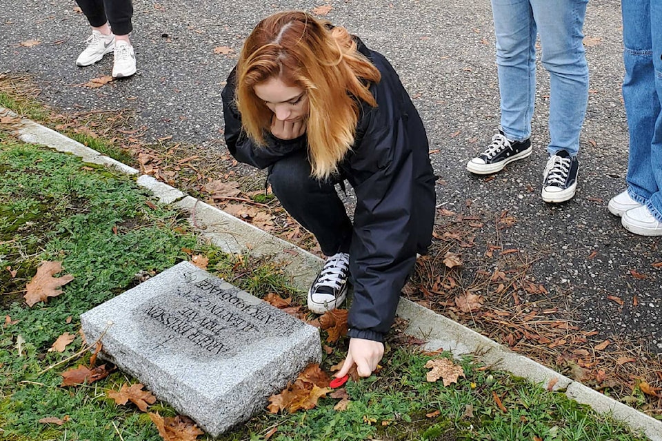 W.L. Seaton student Danica Cowley lays a poppy at the grave of Second World War veteran Pvt. Arger Brisson during the No Stone Left Alone ceremony Wednesday, Nov. 4, at the Pleasant Valley Cemetery in Vernon. (Roger Knox - Morning Star)