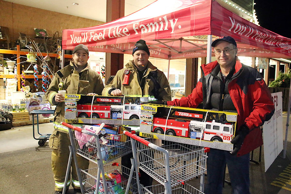 Lake Cowichan firefighters Adam Elliott and Dave Janzen happily accept donations of toys from Dave Allen at the firefighters’ annual toy drive, set up outside Country Grocer last week. (Lexi Bainas/Gazette)