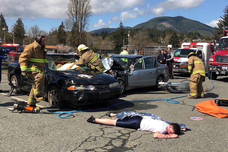 Lake Cowichan volunteer firefighters work to extract the driver from a vehicle while other first responders get to work helping survivors. (Sarah Simpson/Citizen)